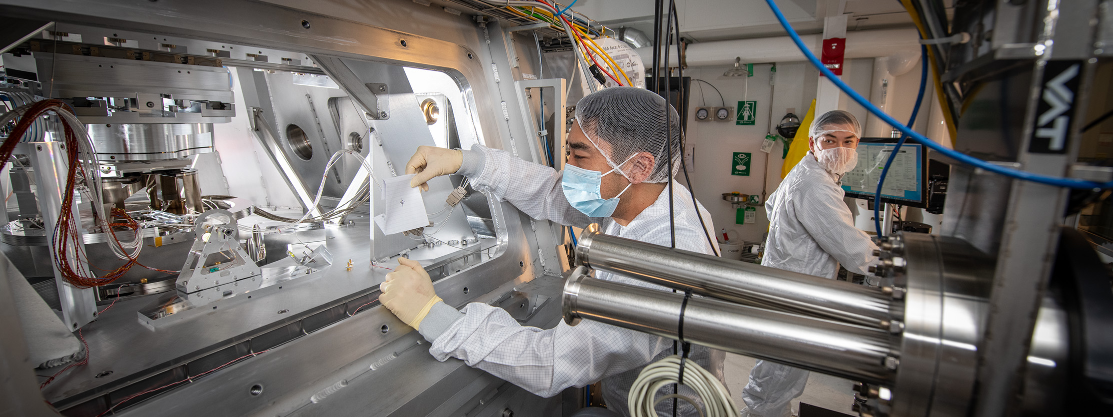 A pair of researchers in PPE check the alignment of light as it enters the CXRO high-resolution camera.