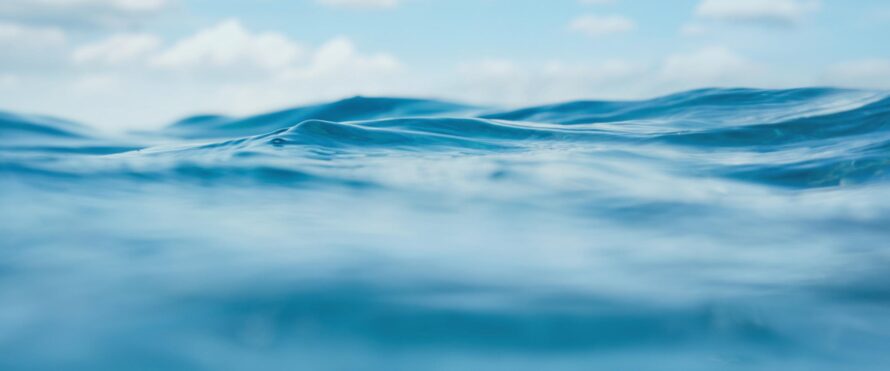 Detailed view of ocean waves rolling in, creating white foam at the surface.