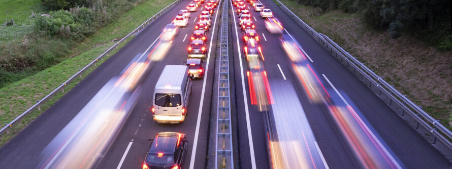 A busy highway experiencing heavy traffic, with vehicles lined up and barely moving in both directions.