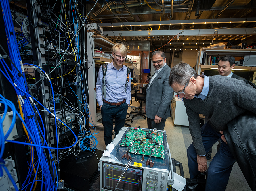 Irfan Siddiqi leads a tour for IQM representatives in the AQT labs at UC Berkeley, with a group gathered around a machine.