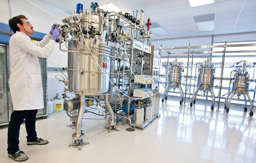 scientist in lab coat adjusting instruments on a vat in a lab